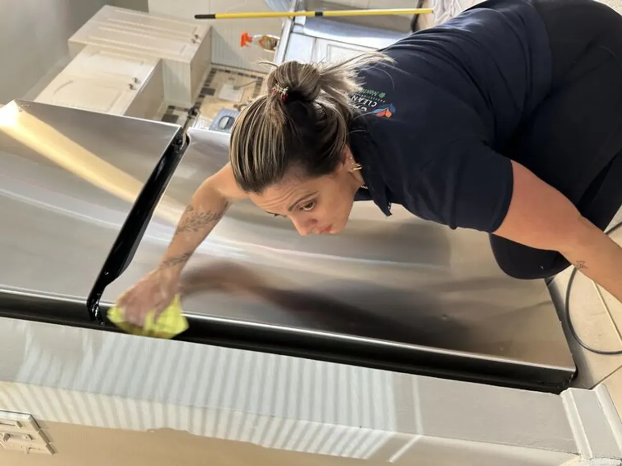 A uniformed Capital Clean Care team member detailing a refrigerator in a DMV home